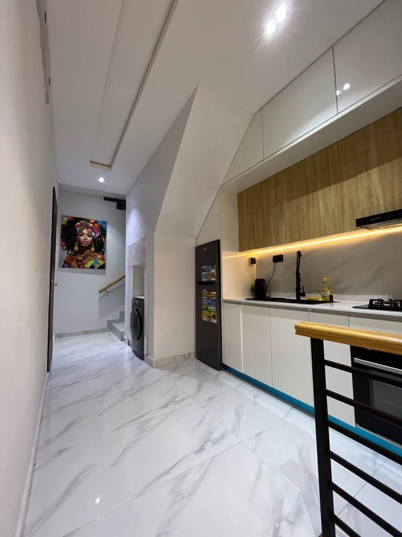Galley kitchen with oak upper cabinets, white base units and a black metal stair balustrade