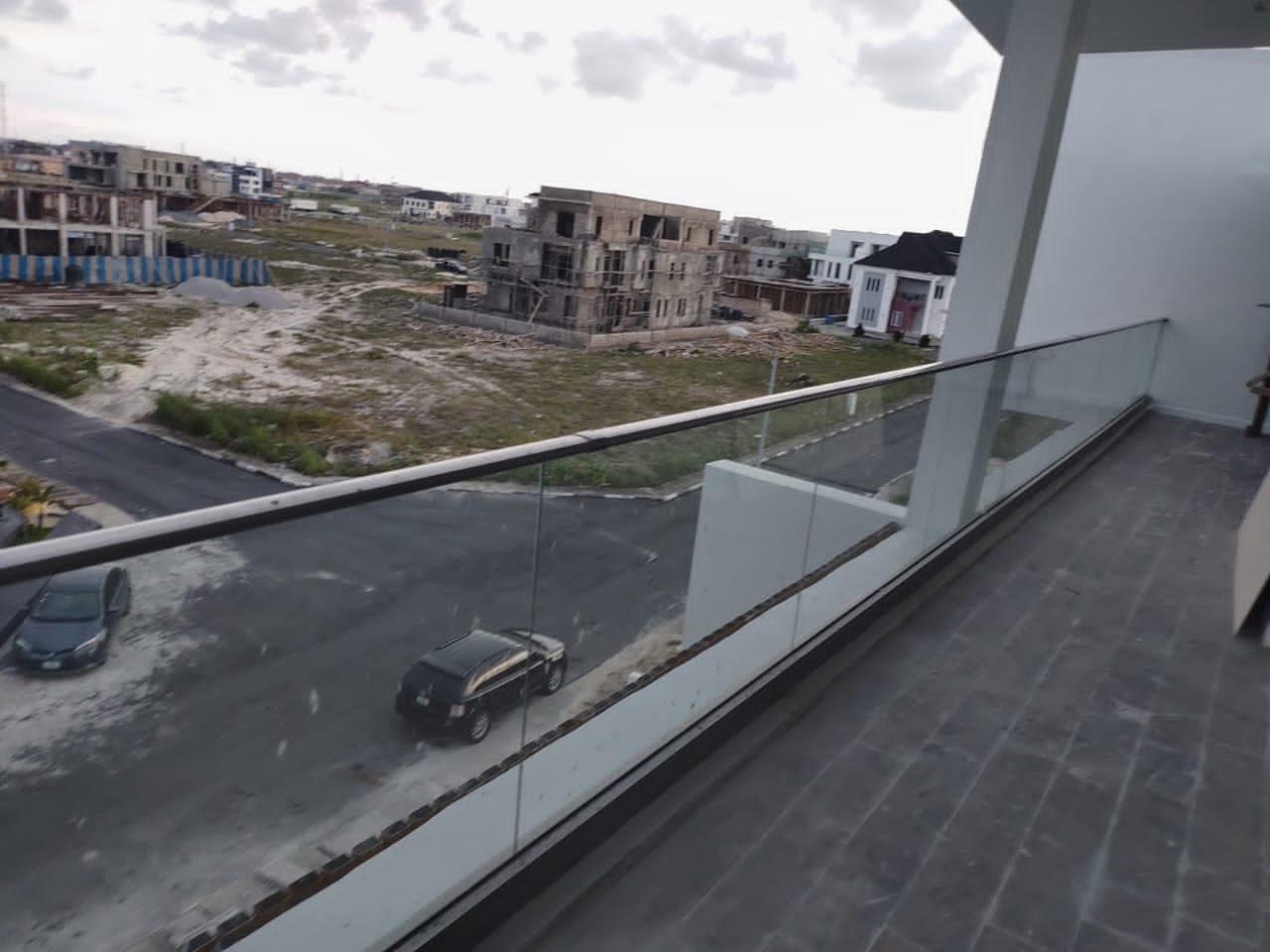 Long frameless glass balcony balustrade with a steel handrail overlooking an estate road