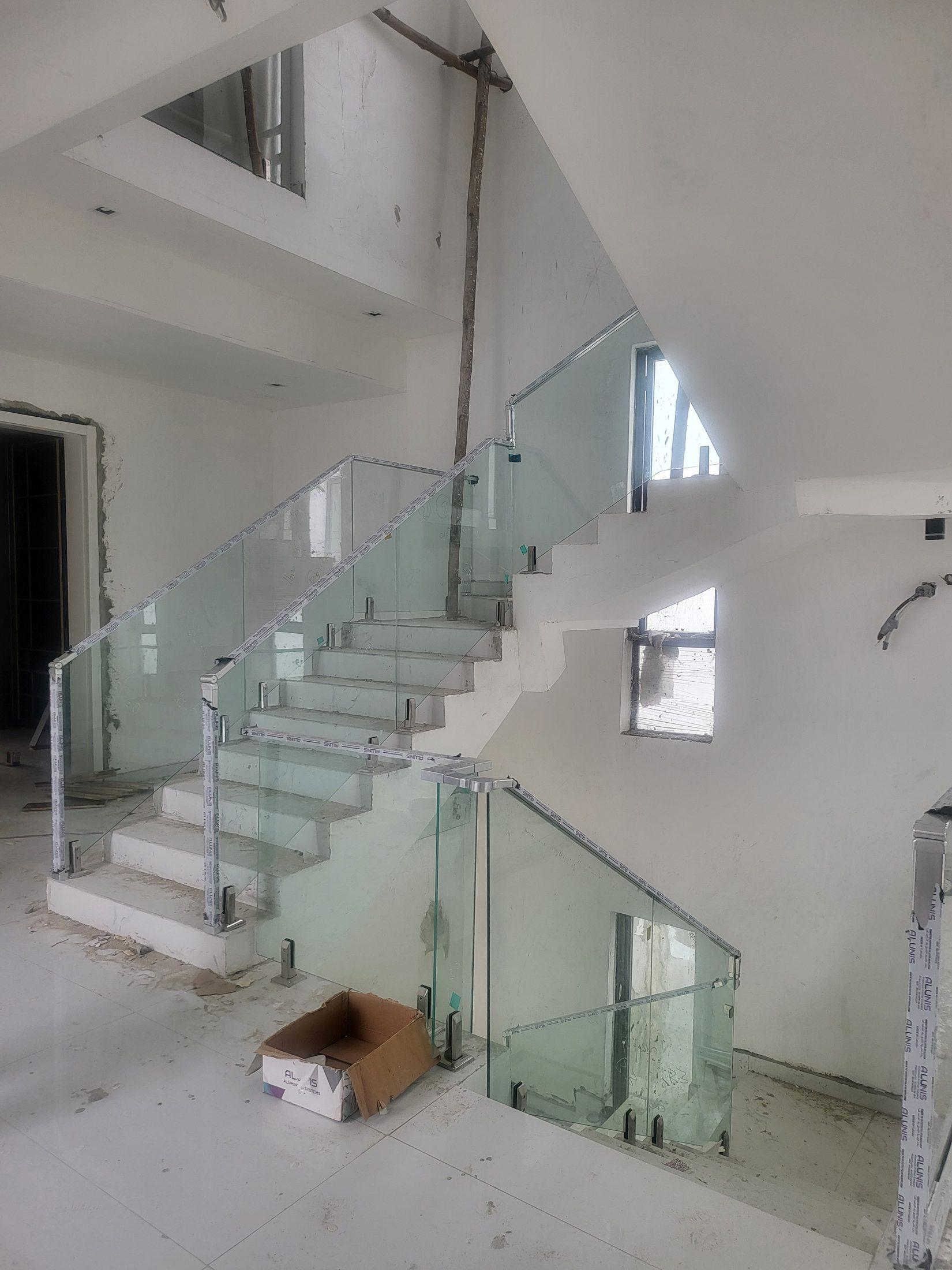 Glass staircase balustrade with steel spigots and handrails, still wrapped in protective film