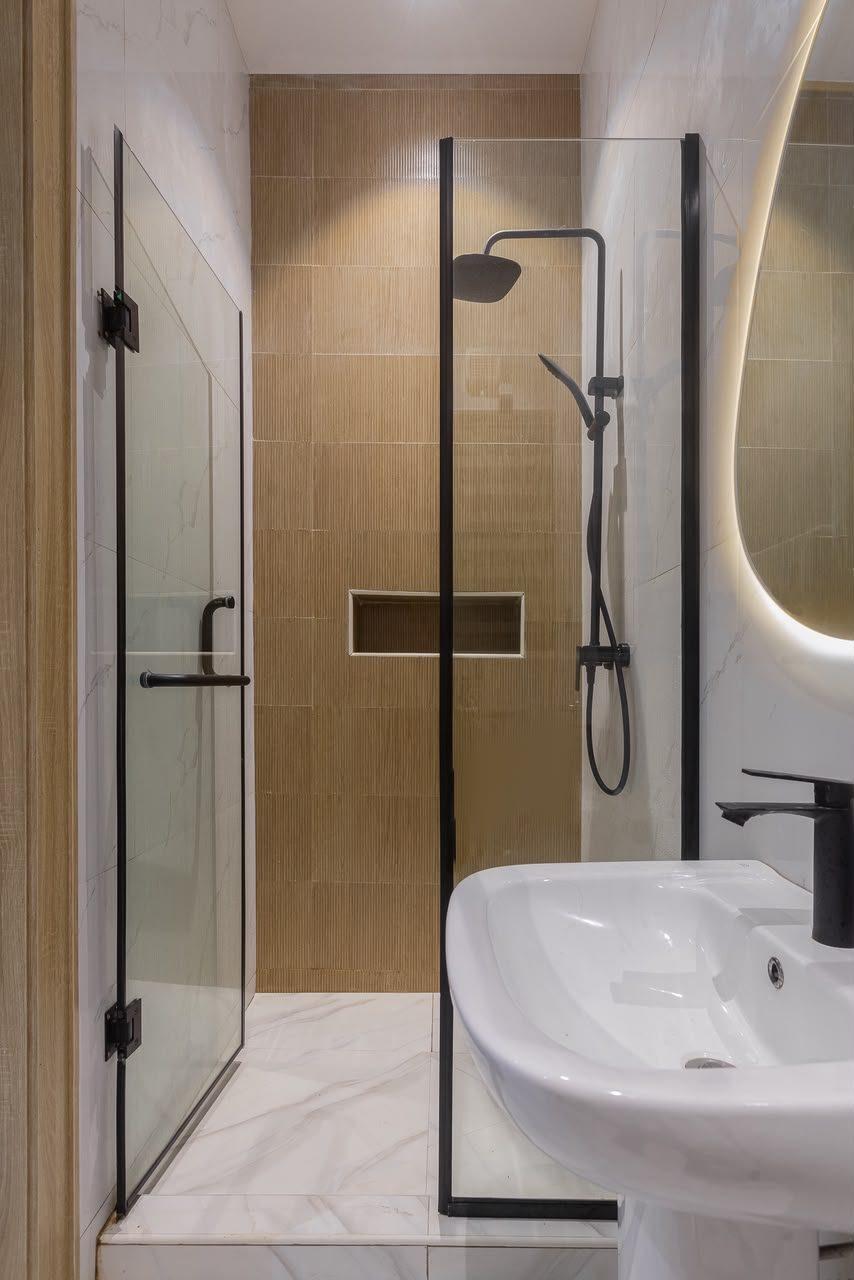 Shower room with black-framed glass enclosure, timber-effect feature tiles, recessed niche and backlit mirror
